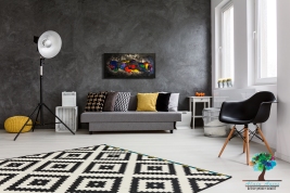 Modern living room with big space in the middle. By the wall comfortable grey couch with pillows and black chair